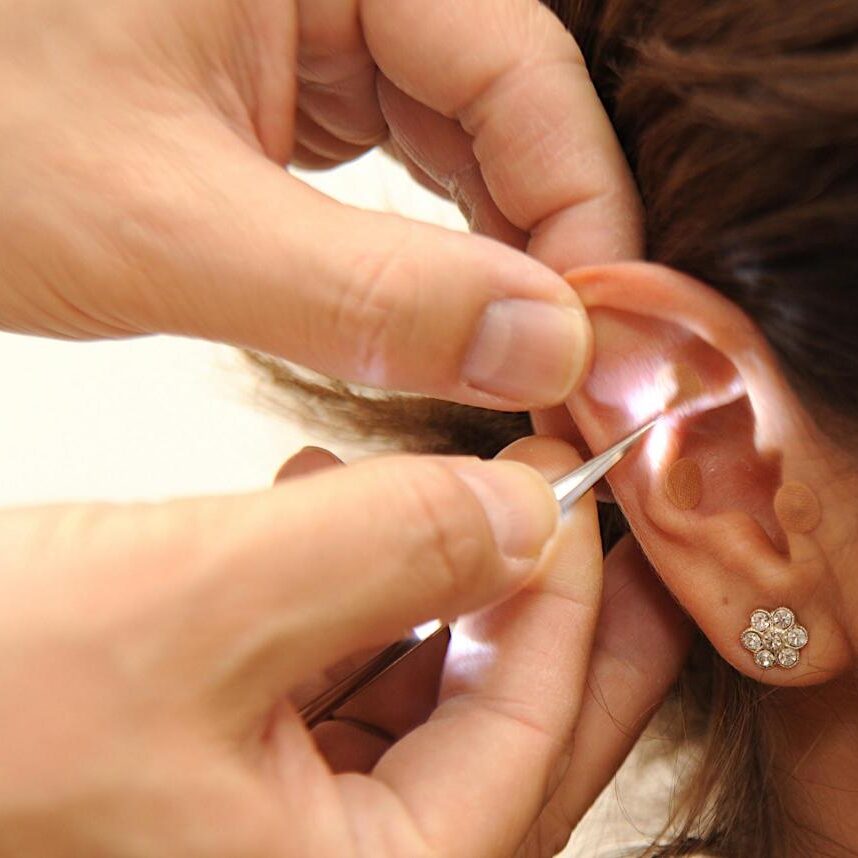 A person putting a needle in their ear